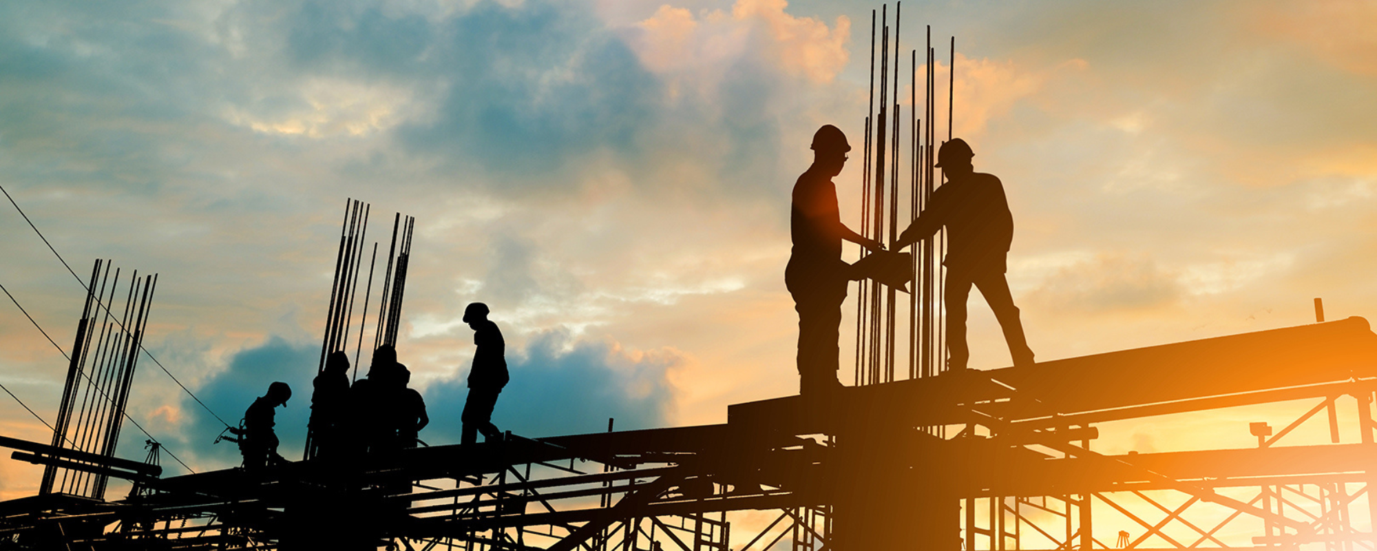 Construction workers on a platform with sunset behind